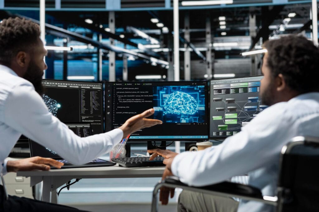 Dos ingenieros señalando pantallas con datos en una sala de control